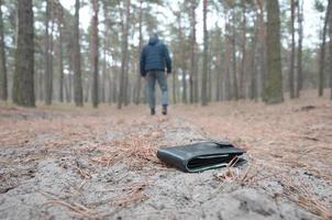 jeune homme perd son sac à main avec des billets en euros sur le chemin du bois de sapin d'automne russe. insouciance et perte de concept de portefeuille photo