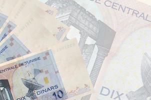 Les billets de 10 dinars tunisiens sont empilés sur fond de gros billets semi-transparents. arrière-plan abstrait des affaires photo