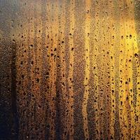 la texture du verre embué avec beaucoup de gouttes et de gouttes de condensation contre la lumière du soleil à l'aube. image de fond photo