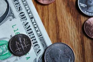 pièces d'un dollar et billets d'un dollar éparpillés sur une table en bois, pièces d'un dollar à plat. photo