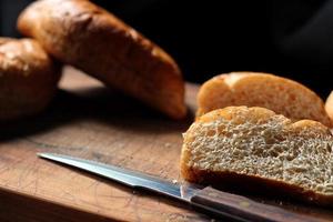 des bolillos de blé ou du pain de grains entiers fraîchement cuits à servir étaient coupés sur une planche à découper en bois. photo