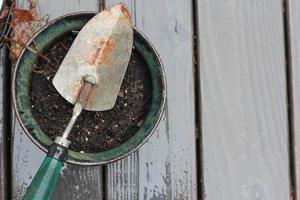 une petite pelle est placée sur un pot de fleurs à l'arrière-plan comme un balcon en bois détrempé par la pluie. photo