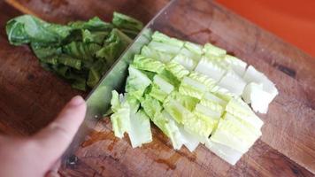 légumes coupés sur une planche à découper en bois avec un couteau. photo