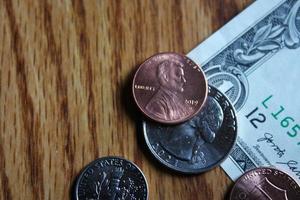 pièces d'un dollar et billets d'un dollar éparpillés sur une table en bois, pièces d'un dollar à plat. photo
