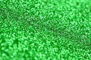 une énorme quantité de paillettes décoratives vertes. image de fond avec des lumières bokeh brillantes à partir de petits éléments photo