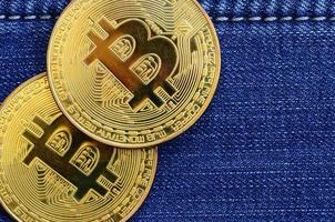deux bitcoins dorés se trouvent sur un tissu de jeans bleu. nouvelle monnaie virtuelle. nouvelle crypto-monnaie sous la forme de pièces photo