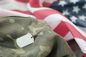 Perles militaires argentées avec étiquette de chien sur le drapeau en tissu des États-Unis et uniforme de camouflage photo