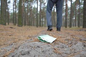 jeune homme perd ses billets d'argent en euros sur le chemin du bois de sapin d'automne russe. négligence et concept de perte d'argent photo