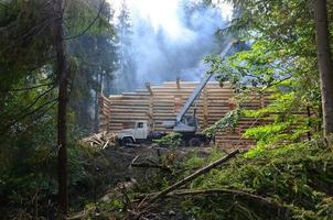 le processus de construction d'une maison en bois à partir de poutres en bois de forme cylindrique. grue en état de marche photo