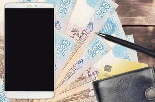 200 factures de hryvnias ukrainiennes et smartphone avec sac à main et carte de crédit. paiements électroniques ou concept de commerce électronique. achats en ligne et affaires avec des appareils portables photo