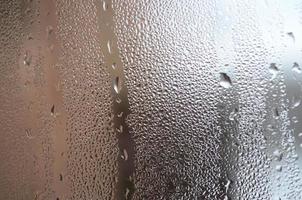 la texture d'un verre embué avec beaucoup de gouttes et de flux de condensation. image de fond photo