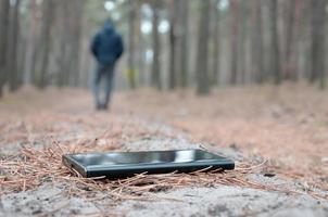 jeune homme perd son smartphone sur le chemin du bois de sapin d'automne russe. négligence et perte d'un concept d'appareil mobile coûteux photo