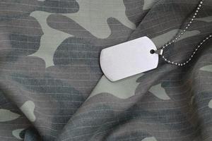 Perles militaires argentées avec étiquette de chien sur l'uniforme de fatigue camouflage photo