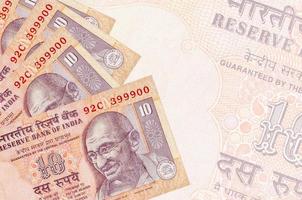 10 billets de roupies indiennes sont empilés sur fond de gros billets semi-transparents. arrière-plan abstrait des affaires photo