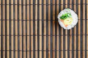 le rouleau de sushi est posé sur un tapis de couture en paille de bambou. cuisine asiatique traditionnelle. vue de dessus. minimalisme à plat tourné avec espace de copie photo