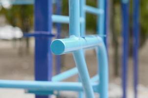 bars sportifs en bleu sur le fond d'un terrain de sport de rue pour l'entraînement en athlétisme. équipement de gym athlétique en plein air. photo macro avec mise au point sélective et arrière-plan extrêmement flou