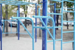 bars sportifs en bleu sur le fond d'un terrain de sport de rue pour l'entraînement en athlétisme. équipement de gym athlétique en plein air. photo macro avec mise au point sélective et arrière-plan extrêmement flou