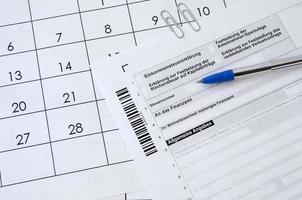 le formulaire fiscal allemand avec un stylo se trouve sur le calendrier du bureau. concept de paiement d'impôt en allemagne photo