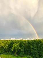 arc-en-ciel de couleur vive dans le ciel. un double arc-en-ciel de couleurs différentes est apparu après la pluie dans la ville. un phénomène naturel magnifique et romantique. les gouttes de pluie se reflètent dans la couleur photo