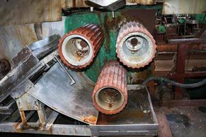 de grands rouleaux métalliques roulent avec les dents des engrenages de la chaîne de production, une bande transporteuse dans l'atelier d'une raffinerie de construction de machines chimiques pétrochimiques industrielles avec des machines d'équipement photo