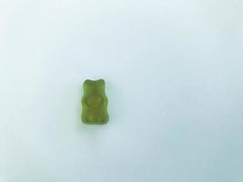 ours gélatineux vert sur fond blanc mat. figurine gommeuse en forme d'animal. bonbons pour bébé. figurine douce et appétissante. dessert hypercalorique pour enfants et adultes photo