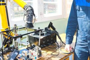 un électricien travaillant dans une robe travaille professionnellement sur une table pour la réparation dans un atelier pour l'électronique à distance et la fabrication de pièces et de pièces de rechange photo