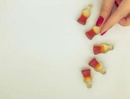 dessert à la marmelade. gélifiés sous forme de bouteille avec de la limonade noire. figurine appétissante, une fille aux ongles rouges tenant un bonbon. forme de bonbon semi-circulaire photo