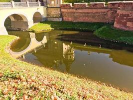 un grand mur de terre en briques rouges est une protection solide et un fossé avec la guerre d'un ancien château médiéval au centre de l'europe et d'une rivière avec de l'eau photo