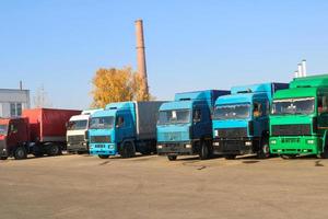 de gros camions lourds avec cabines et remorques se tiennent dans une rangée prêts pour la livraison de marchandises à la raffinerie industrielle sur fond de tuyaux, magasin de logistique de transport photo