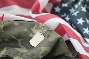 Perles militaires argentées avec étiquette de chien sur le drapeau en tissu des États-Unis et uniforme de camouflage photo
