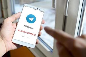 kharkov, ukraine - 27 avril 2018 un téléphone mobile avec l'écran de l'application télégramme avec un panneau d'interdiction. roskomnadzor a bloqué le service de télégramme en russie. l'accès au messager du télégramme est fermé photo