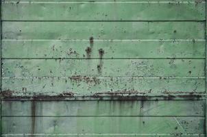 texture d'un vieux mur de métal vert avec des dommages importants dus à l'exposition à des conditions météorologiques défavorables et à l'humidité photo