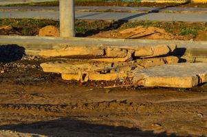 des dalles de béton reposent sur un sol humide sur lequel circulent des engins de chantier. traces de tracteur sur l'argile. des morceaux de béton sont nécessaires pour construire de nouvelles maisons photo