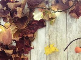 cadre et feuilles d'automne naturelles colorées brun rouge jaune, érable sur fond de planches de bois. l'arrière-plan. texture photo