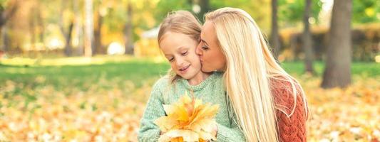 femme et fille tenant des feuilles jaunes d'automne photo