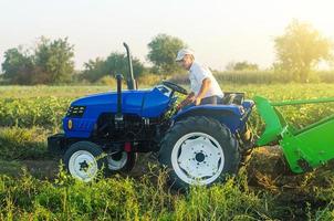 un agriculteur sur un tracteur se prépare à entrer dans le champ et à commencer la récolte. l'agriculture et les terres agricoles. récolter les pommes de terre en automne. accélérer le travail avec la technologie et les machines. machines agricoles. photo