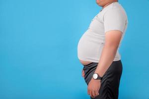 gros homme montrant son ventre sur fond bleu dans le studio photo