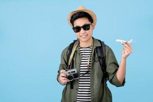 touristes asiatiques souriant joyeusement tenant un avion et un appareil photo avec des vacances sur fond bleu. fond isolé.