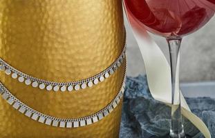 chaîne en argent sur une bouteille en or et un verre de vin