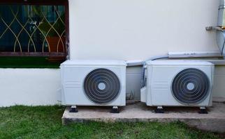 blanc deux unités de ventilateur de conditionnement installées sur le sol en ciment du bâtiment, mise au point douce et sélective. photo