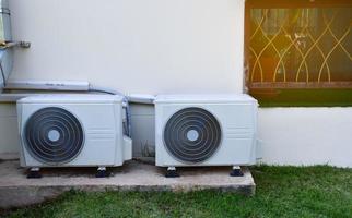 blanc deux unités de ventilateur de conditionnement installées sur le sol en ciment du bâtiment, mise au point douce et sélective. photo