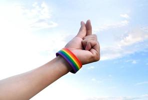 main d'humain qui a un bracelet arc-en-ciel et fait un mini coeur ou signe d'amour par les doigts, concept pour présenter l'amour aux genres lgbtq à toutes les personnes qui avaient la diversité des genres dans le monde. photo