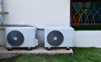 blanc deux unités de ventilateur de conditionnement installées sur le sol en ciment du bâtiment, mise au point douce et sélective. photo