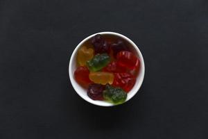 ours de marmelade de gelée dans une tasse en céramique sur fond noir. gros plan de bonbons colorés à la marmelade. photo