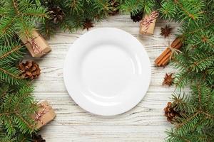 vue de dessus. assiette vide en céramique ronde sur fond de noël en bois. concept de plat de dîner de vacances avec un décor de nouvel an photo