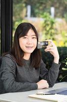 jeune femme tenant une carte de crédit avec un ordinateur portable sur le pont photo