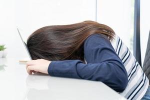 jeune femme cheveux longs s'endormir sur un bureau avec un ordinateur portable photo