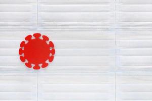molécule de coronavirus découpée en feutre rouge sur fond de masques médicaux bleu clair. pandémie mondiale. statistiques sur les maladies, vaccinations, système de santé, médecine, quarantaine. notion de covid-19. photo