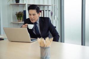 concept d'apprentissage, de réunion, de travail et d'apprentissage en ligne en ligne. homme d'affaires asiatique décontracté étudiant un cours en ligne, se rencontrant via un ordinateur portable au bureau. photo