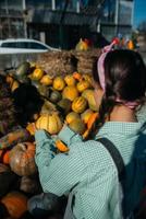 femme avec une petite citrouille parmi la récolte d'automne photo